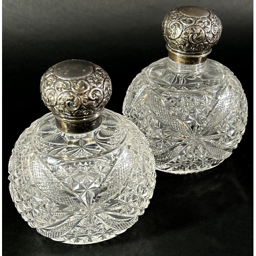 197 - A pair of cut glass dressing table bottles with silver floral engraved caps