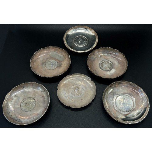 210 - A collection of seven silver dishes with coins inserted depicting different heads of state, together... 