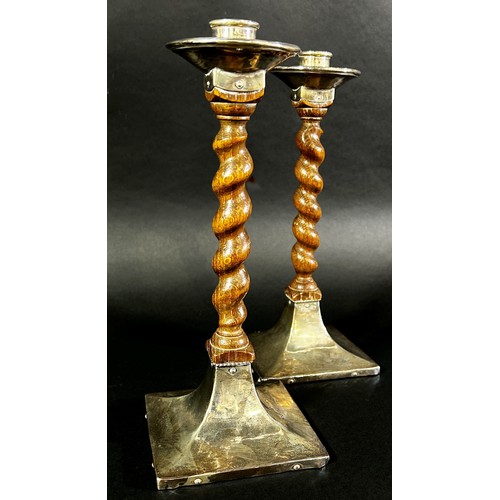 214 - A pair of early 20th century English Arts & Crafts oak barley twist candlesticks with silver sconces... 