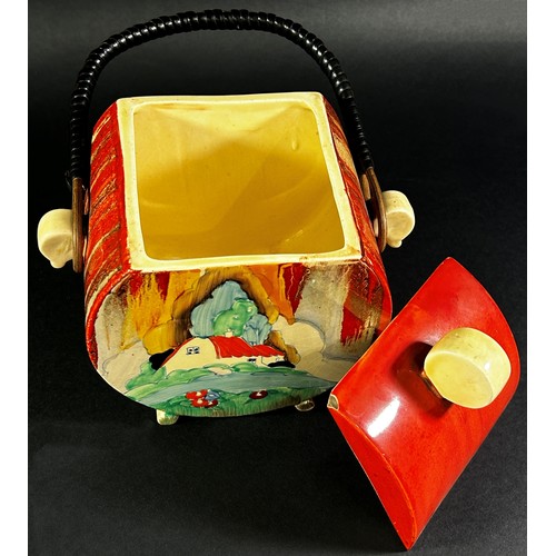 64 - A Clarice Cliff Bizarre biscuit barrel and cover with wicker handle, red roof cottage pattern