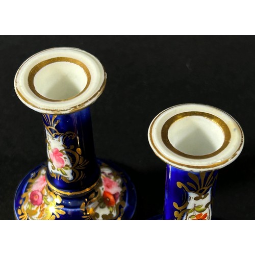 410 - A miniature pair of Coalport candlesticks decorated with hand painted sprays of flowers and gilding ... 