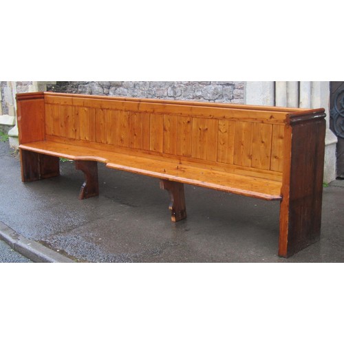 1020 - A pine church pew with shaped planked seat and boarded back beneath moulded rail, one end with pierc... 