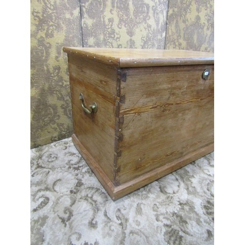 1063 - A stripped pine blanket box with hinged lid and brass drop side carrying handles, 56 cm high x 91 cm... 