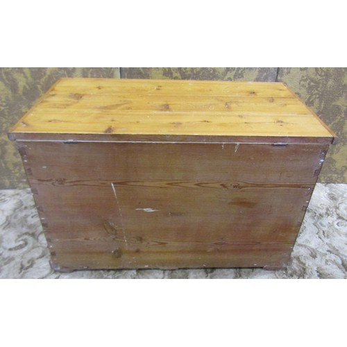 1063 - A stripped pine blanket box with hinged lid and brass drop side carrying handles, 56 cm high x 91 cm... 