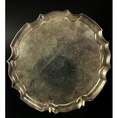 234 - A silver scalloped edge salver raised on four scrolled feet, Sheffield 1934, maker James Dixon & Son... 