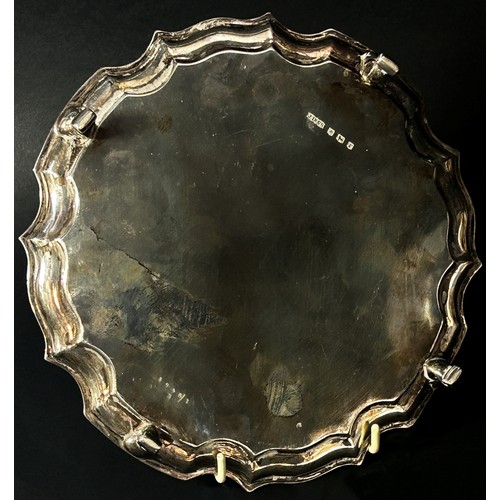 234 - A silver scalloped edge salver raised on four scrolled feet, Sheffield 1934, maker James Dixon & Son... 