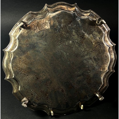 235 - A silver scalloped edge salver on four scrolled pad feet, the matching larger to the previous lot, m... 