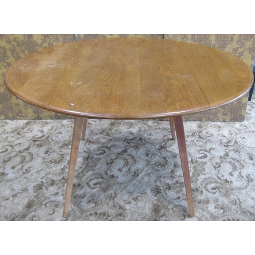 1093 - An Ercol elm and beechwood oval drop leaf dining table raised on splayed square tapered supports, 72... 