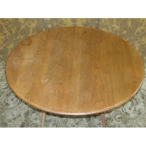 1093 - An Ercol elm and beechwood oval drop leaf dining table raised on splayed square tapered supports, 72... 