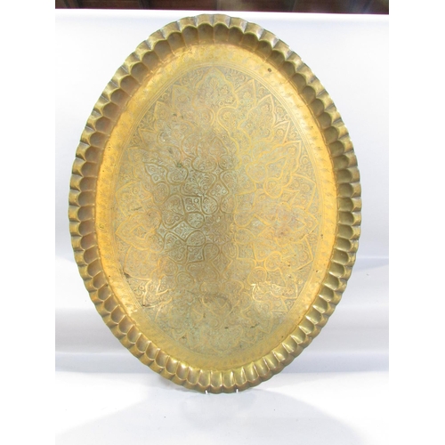 492 - An oval Middle Eastern richly engraved brass tray, 87cm x 65cm, with a wooden stand