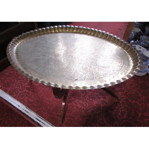 492 - An oval Middle Eastern richly engraved brass tray, 87cm x 65cm, with a wooden stand