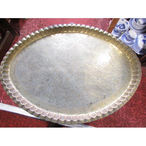 492 - An oval Middle Eastern richly engraved brass tray, 87cm x 65cm, with a wooden stand