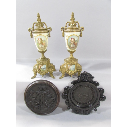 519 - A pair of brass urn shaped clock garnitures with a romantic pastoral scene, a circular tavern scene ... 