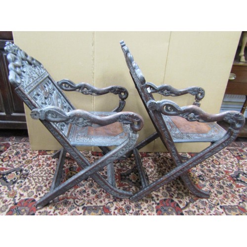 1468 - A pair of 19th century Chinese folding armchairs, profusely carved and detailed with dragons, serpen... 