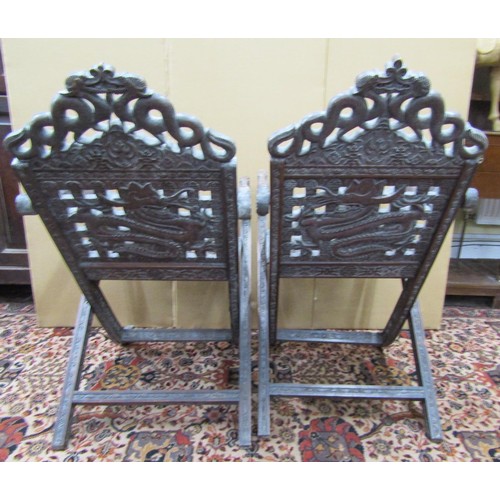 1468 - A pair of 19th century Chinese folding armchairs, profusely carved and detailed with dragons, serpen... 