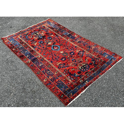 1497 - An old Hamadan woven wool rug, with floral patterns on a predominantly red ground, 190cm x 120cm