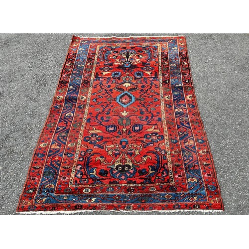 1497 - An old Hamadan woven wool rug, with floral patterns on a predominantly red ground, 190cm x 120cm