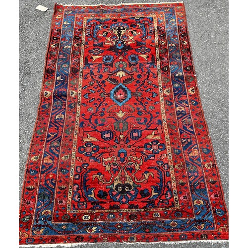 1497 - An old Hamadan woven wool rug, with floral patterns on a predominantly red ground, 190cm x 120cm