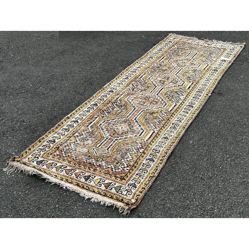 1506 - A faded wool Kazak type runner with four interlocking medallions in pink and yellow tones, 270cm x 1... 