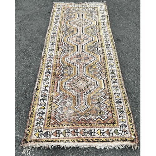 1506 - A faded wool Kazak type runner with four interlocking medallions in pink and yellow tones, 270cm x 1... 