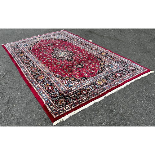 1509 - A Kasahan Persian carpet with a central blue medallion in a red surround of flowers, 310cm x 200cm.