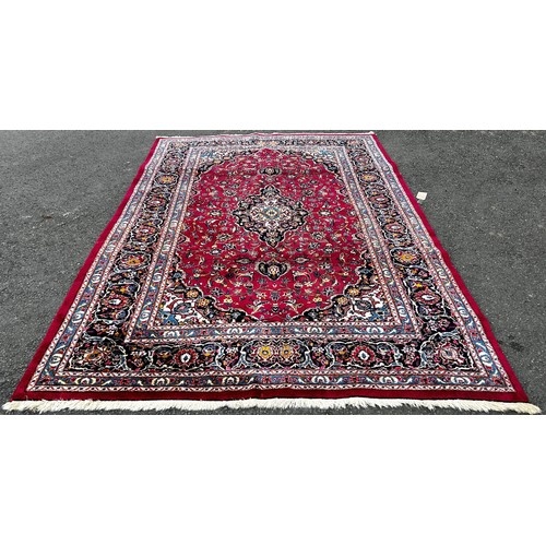 1509 - A Kasahan Persian carpet with a central blue medallion in a red surround of flowers, 310cm x 200cm.