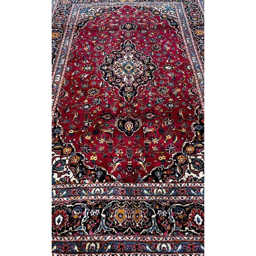 1509 - A Kasahan Persian carpet with a central blue medallion in a red surround of flowers, 310cm x 200cm.