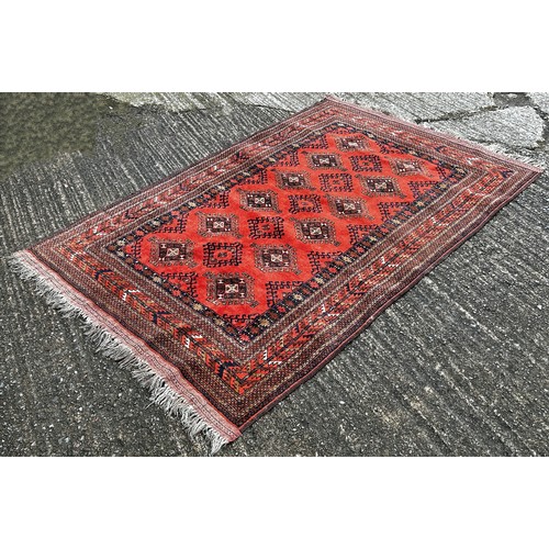 1528 - A old Hamadan carpet with a central panel of hooked medallions on a red brick ground, 200cm x 130cm.