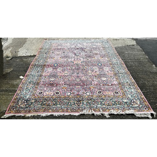 1529A - A large Persian design carpet with an all over floral pattern on a pink ground, 350cm x 250cm.