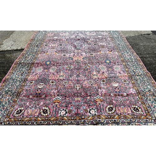 1529A - A large Persian design carpet with an all over floral pattern on a pink ground, 350cm x 250cm.