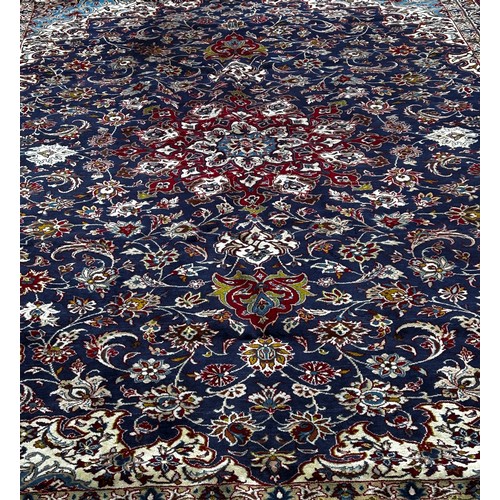 1530A - A large Isfahan carpet with a central star burst medallion with an all over floral pattern on a blue... 