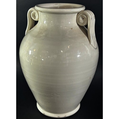 100 - A large cream glazed urn shaped studio ware vase with scroll handles, 32cm high