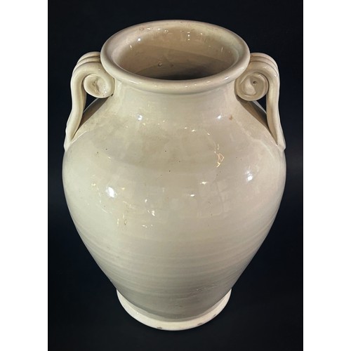 100 - A large cream glazed urn shaped studio ware vase with scroll handles, 32cm high