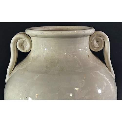 100 - A large cream glazed urn shaped studio ware vase with scroll handles, 32cm high