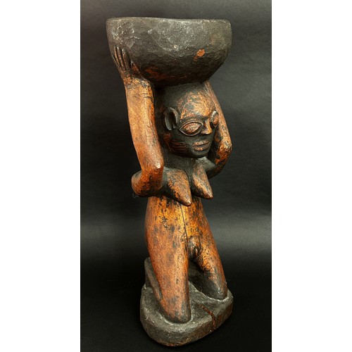 1741 - An old African carved hardwood figural tazza / vessel, in the form of a nude figure kneeling, holdin... 