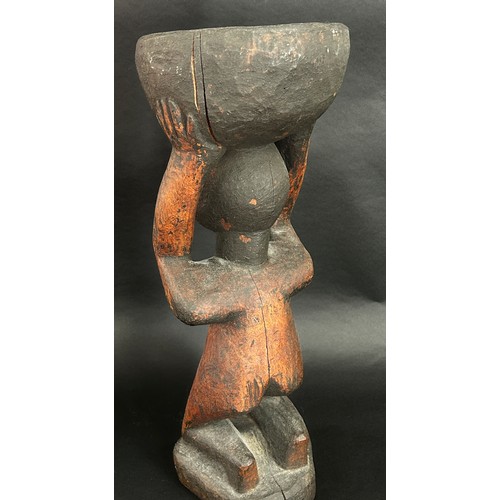 1741 - An old African carved hardwood figural tazza / vessel, in the form of a nude figure kneeling, holdin... 