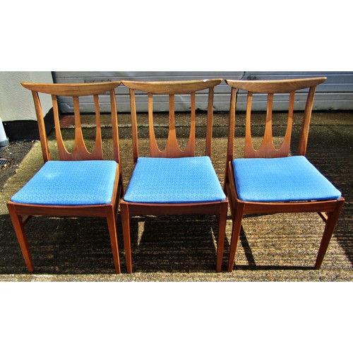 Three mid-20th century teak dining chairs with stick backs and upholstered seats on square tapered legs
