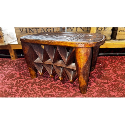 1736 - A central African carved hardwood stool of rounded, rectangular form, the chip-carved top decoration... 