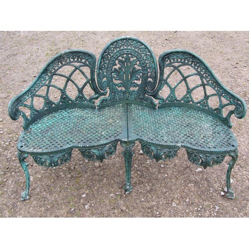 A weathered green painted cast alloy garden bench with shaped outline and decorative pierced lattice, anthemion and geometric detail raised on swept and scrolled supports, 140 cm wide