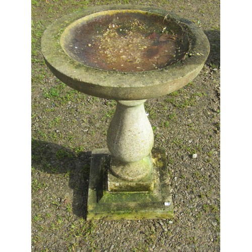 80 - A weathered cast composition stone bird bath, raised on a baluster pedestal and square stepped base,... 