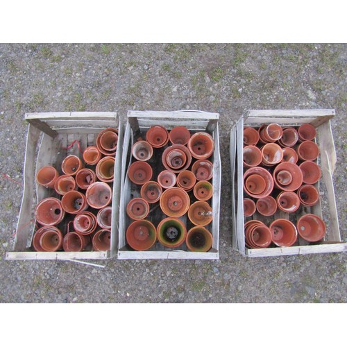 83 - Three weathered wooden crates containing a quantity of terracotta flower pots of varying size and de... 