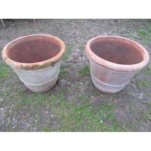 65 - A pair of large weathered terracotta planters of circular tapered and simple ribbed form, 56 cm high... 