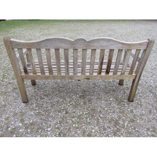 84 - A Bridgman weathered teak three seat garden bench with slatted seat and back beneath a shaped rail w... 