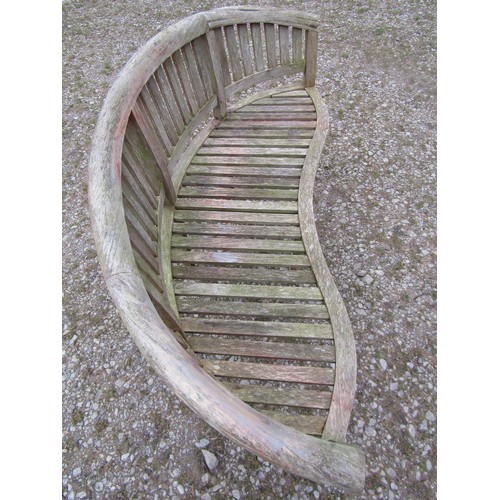 88 - A weathered teak banana shaped garden bench, 156cm wide  (af)