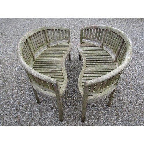 74 - A pair of weathered teak banana shaped garden benches with loose seat cushions, 160 cm wide