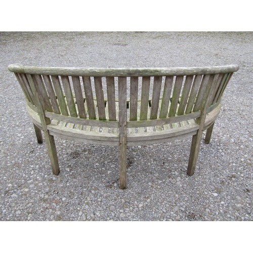 74 - A pair of weathered teak banana shaped garden benches with loose seat cushions, 160 cm wide