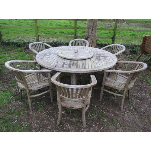 A good quality large weathered (silvered teak) circular garden table with slatted panelled top and revolving lazy Susan, raised on simple turned supports, 180cm diameter, together with a set of six chairs with horseshoe shaped slatted backs and seats, raised on square tapered forelegs, (7)