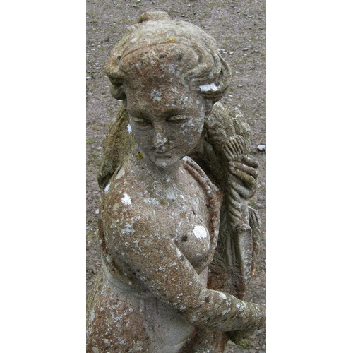 114 - A weathered cast composition stone garden ornament in the form of a standing classical maiden clutch... 