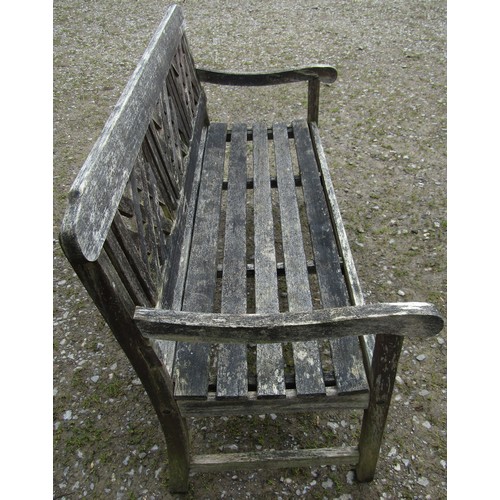 155 - A weathered three seat garden bench with slatted seat and lattice panelled back beneath a shaped rai... 