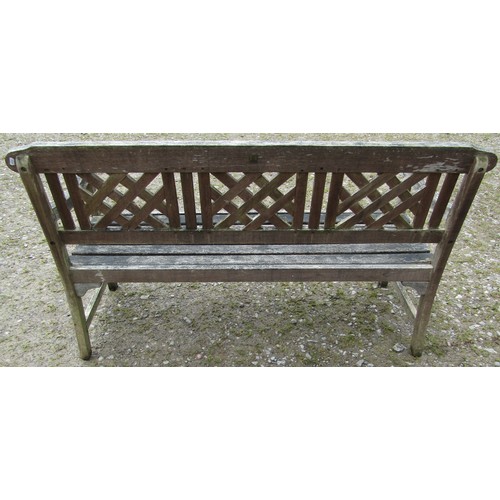 155 - A weathered three seat garden bench with slatted seat and lattice panelled back beneath a shaped rai... 